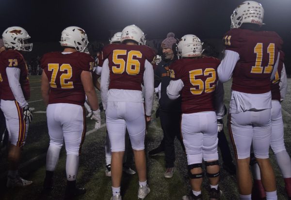Coach Brady Walz gathers the football team together between plays during the Johnston Dragons game on Oct. 27. For Ankeny’s football players, it is important to balance an intense practice schedule with academics throughout the week.
