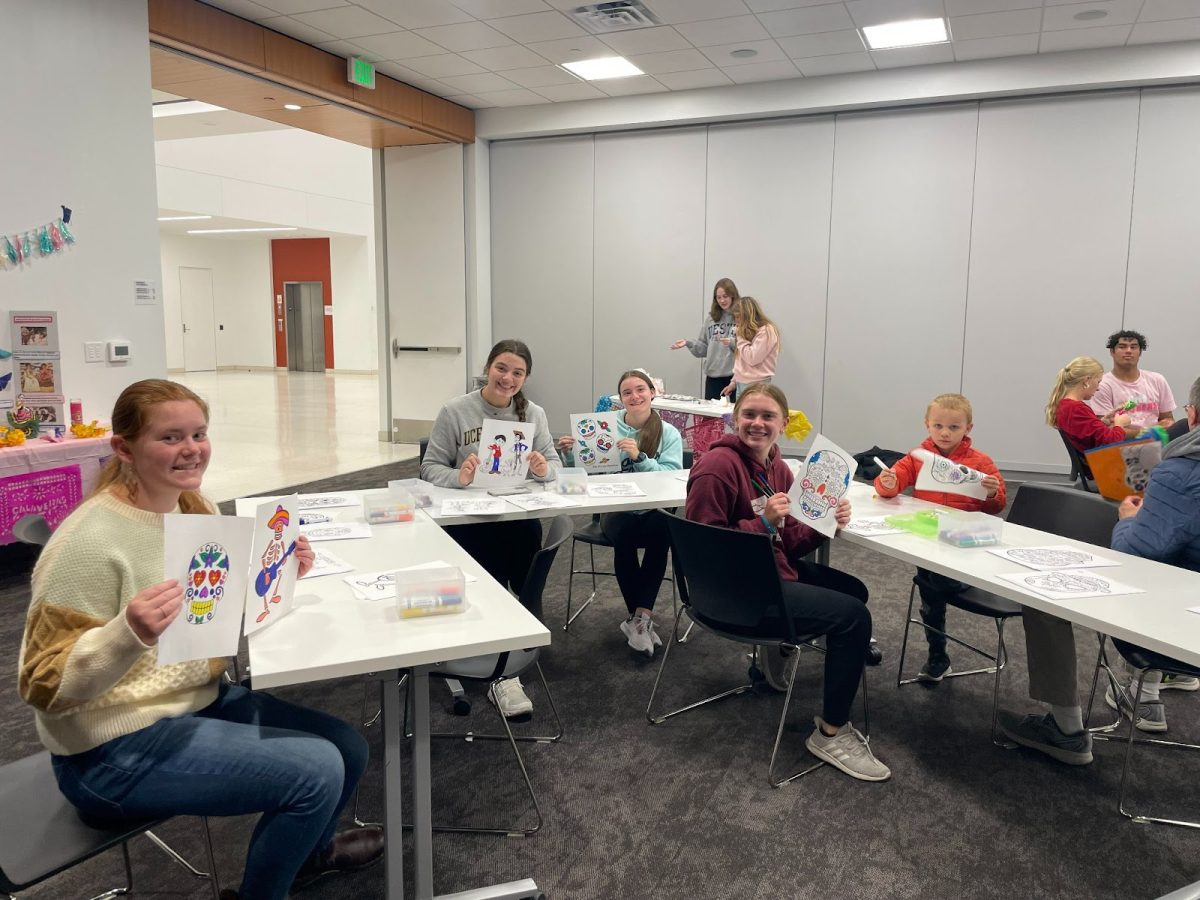 Seniors Brenna Fast and  Ava Tomlinson, and juniors Faith Spoelstra, and Kaylyn Miller showcase their coloring pages. Students worked the coloring station helping kids color  sheets in the Day of the Dead celebration hosted by Spanish Honor Society at Kirkendall Library. “We put this event together to expand the knowledge of the people in our community about Dia de los Muertos and Spanish culture,” Miller said.