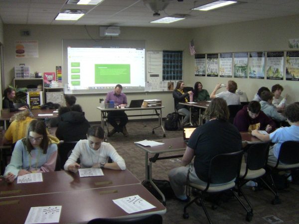 Students collaborate during Hawk Time as they tackle the New York Times crossword puzzle together, fostering a spirit of camaraderie and friendly competition.