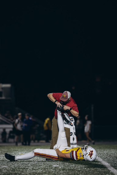 AHS athletic trainer Grant Waller stretches defensive end Liam Howard on the sideline of the Homecoming football game versus Sioux City East. “The body is meant to move, and when the body doesn't move correctly, that’s when you start to get injuries,” Waller said. Photo published with permission by Dylan Shoemaker
